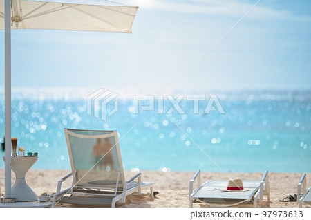 Umbrellas and deck chairs on the white sandy beach of an Asian luxury resort hotel 97973613