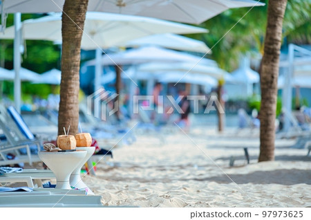 Deck chairs and coconut fruit on the sandy beach of an Asian resort hotel 97973625
