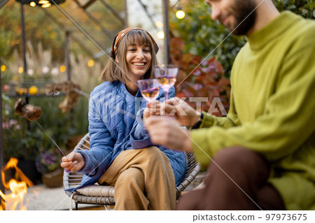 Young couple spending dinner time by the fire at backyard 97973675
