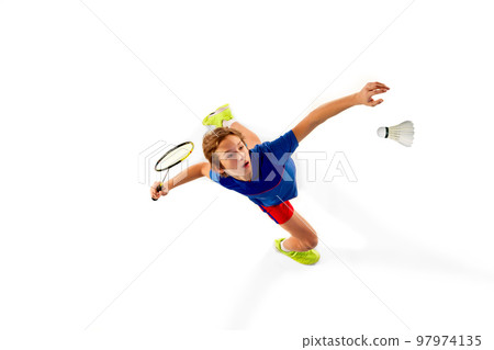 Top View. Concentrated teen boy in uniform playing badminton, hitting shuttlecock with racket isolated over white background Top View. Concentrated teen boy in uniform playing badminton, hitting shuttlecock with racket isolated over white background 97974135