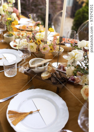 Wedding table for guests, decorated with candles, are served with cutlery and crockery and covered with yellow tablecloth 97974301