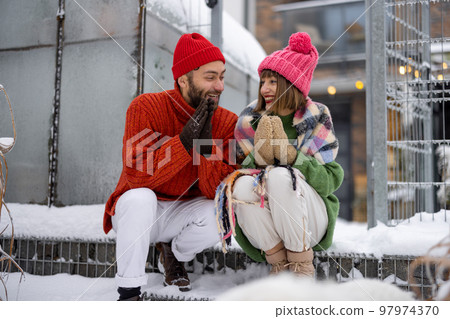 Young couple sit together on a porch of their house on winter 97974370