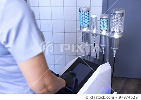 Faceless beautician using massager to remove fat from hips of anonymous customer 97974529