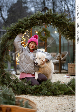 Woman with a dog in Christmas wreath at backyard Woman with a dog in Christmas wreath at backyard 97974830