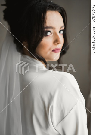 Luxury bride in white dress posing while preparing for the wedding ceremony Luxury bride in white dress posing while preparing for the wedding ceremony 97975572