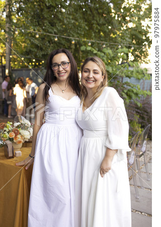 Bride communicate with brunette bridemaid against the wedding table 97975884