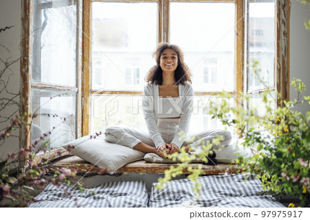 African American ethnic woman wearing white clothes sitting in yoga pose 97975917