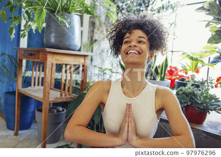 African American ethnic woman wearing sportswear sitting in yoga pose 97976296