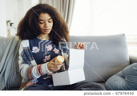 Portrait of smiling afro american lady received package, unpacking cardboard beauty box with cosmetics Portrait of smiling afro american lady received package, unpacking cardboard beauty box with cosmetics 97976430