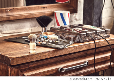 Hairdresser tools on wooden background. Top view on wooden table with scissors, comb, hairbrushes and hairclips, trimmer. 97976717