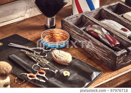Hairdresser tools on wooden background. Top view on wooden table with scissors, comb, hairbrushes and hairclips, trimmer. 97976718