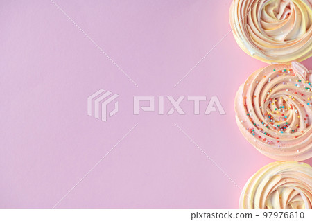 Pink round sweet meringues lie on a pink background on the side Pink round sweet meringues lie on a pink background on the side 97976810