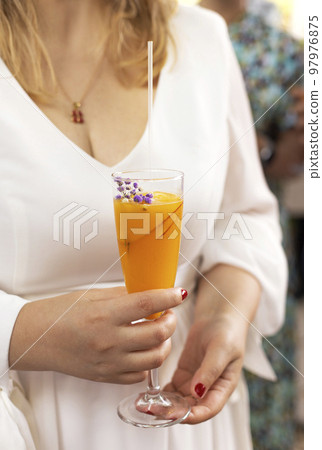Bellini with prosecco and a peach outdoors. Woman holding a glass outdoors Bellini with prosecco and a peach outdoors. Woman holding a glass outdoors 97976875