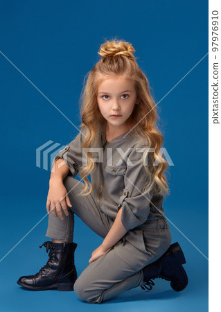 Little girl with a long curly hair in a fashionable clothes Little girl with a long curly hair in a fashionable clothes 97976910
