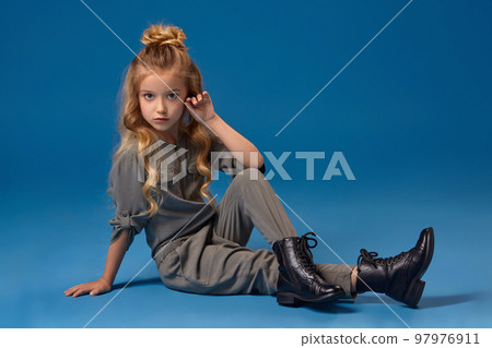 Little girl with a long curly hair in a fashionable clothes Little girl with a long curly hair in a fashionable clothes 97976911