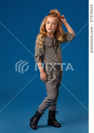 Little girl in a fashionable clothes on blue background Little girl in a fashionable clothes on blue background 97976924
