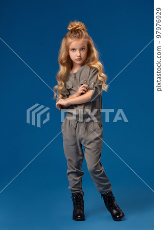 Little girl in a fashionable clothes on blue background Little girl in a fashionable clothes on blue background 97976929