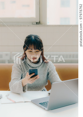 A photo of a female college student doing desk work in a cafe 97978762