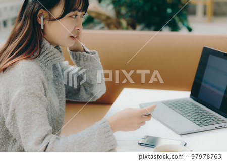 A photo of a female college student doing desk work in a cafe 97978763