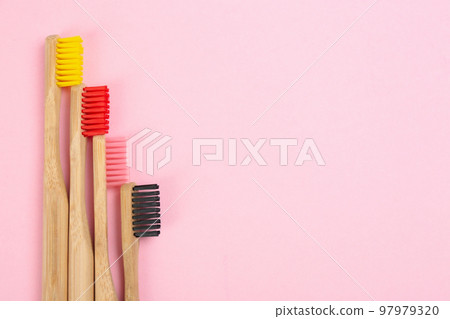 Toothbrushes made of bamboo on pink background, flat lay. Space for text Toothbrushes made of bamboo on pink background, flat lay. Space for text 97979320