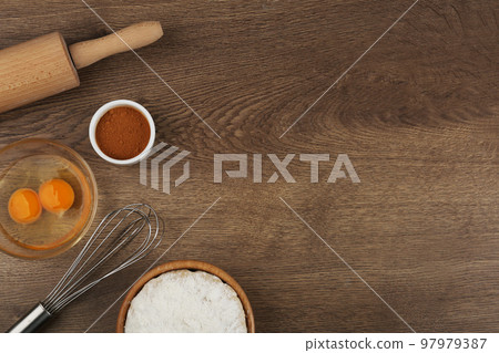 Flat lay composition with raw eggs and other ingredients on wooden table, space for text. Baking pie 97979387