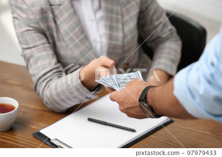 Man giving bribe money to woman at table, closeup Man giving bribe money to woman at table, closeup 97979433