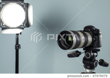Professional video camera and lighting equipment on grey background Professional video camera and lighting equipment on grey background 97979479