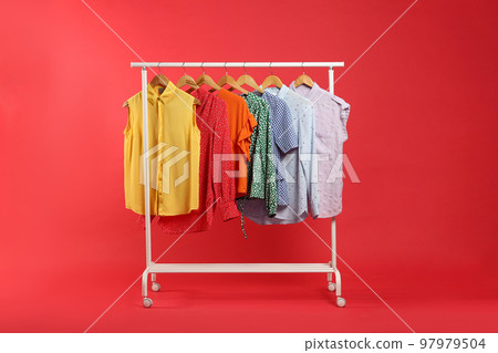 Bright clothes hanging on rack against red background. Rainbow colors 97979504