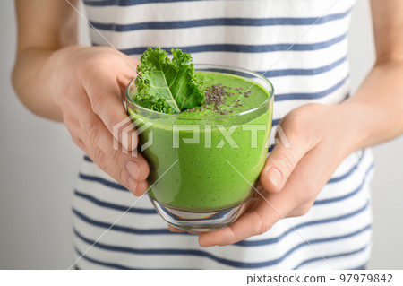 Woman holding tasty kale smoothie with chia seeds on light background, closeup 97979842