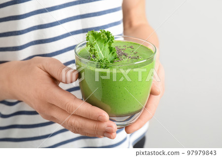 Woman holding tasty kale smoothie with chia seeds on light background, closeup Woman holding tasty kale smoothie with chia seeds on light background, closeup 97979843