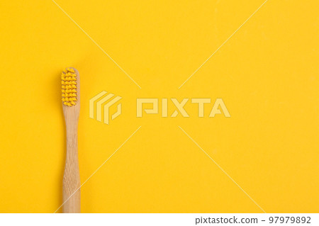 Toothbrush made of bamboo on yellow background, top view. Space for text 97979892