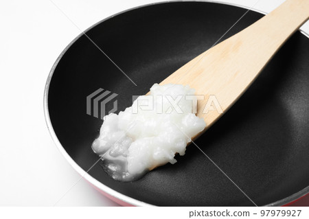 Frying pan with coconut oil and wooden spatula on white background, closeup. Healthy cooking Frying pan with coconut oil and wooden spatula on white background, closeup. Healthy cooking 97979927