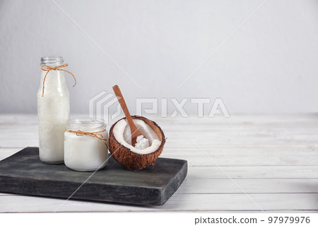 Composition with fresh coconut oil on white wooden table, space for text. Cooking ingredient 97979976