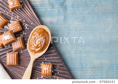 Salted caramel on blue wooden table, top view. Space for text 97980241