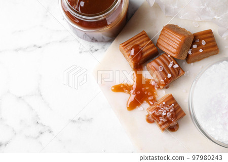 Salted caramel with sauce on marble table, flat lay. Space for text 97980243