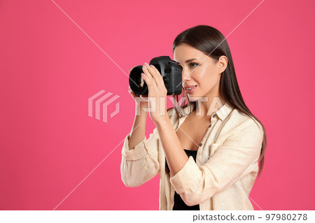 Professional photographer working on pink background in studio. Space for text Professional photographer working on pink background in studio. Space for text 97980278