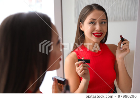 Beautiful woman with red lipstick near mirror Beautiful woman with red lipstick near mirror 97980296