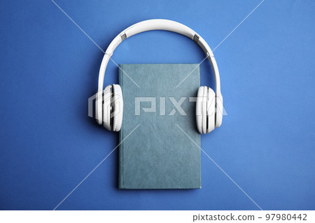 Book and modern headphones on blue background, top view Book and modern headphones on blue background, top view 97980442