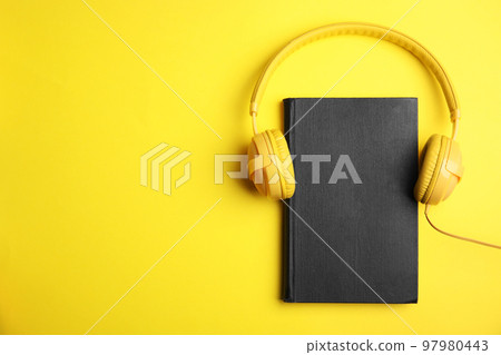 Book and modern headphones on yellow background, top view. Space for text 97980443