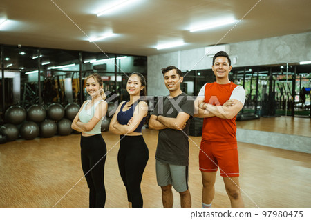 Sporty group of friends with arms crossed in fitness gym 97980475
