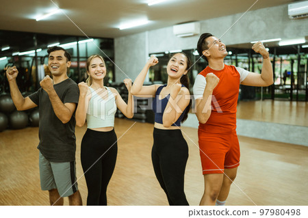 Group of happy diverse young friends standing with fists clenched 97980498