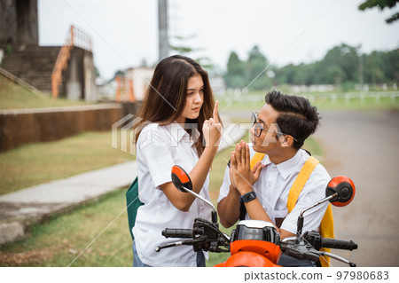 A student girl pointing her middle finger at a boy A student girl pointing her middle finger at a boy 97980683
