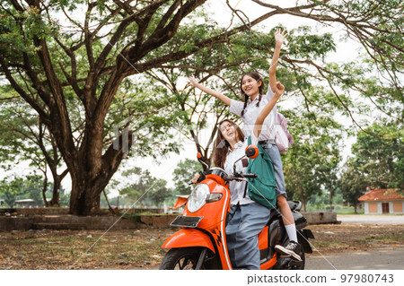Two naughty high school girls ride on a reckless motorbike Two naughty high school girls ride on a reckless motorbike 97980743