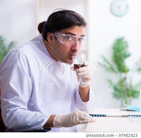Male chemist examining wine samples at lab 97982823