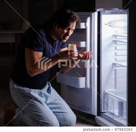 Man breaking diet at night near fridge Man breaking diet at night near fridge 97983262