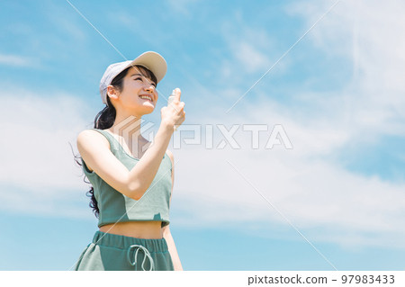 Japanese woman doing antiperspirant spray, UV care, deodorant care before exercising in summer 97983433