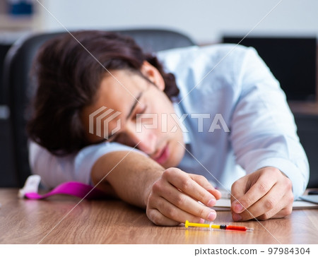 Young man having problems with narcotics at workplace Young man having problems with narcotics at workplace 97984304
