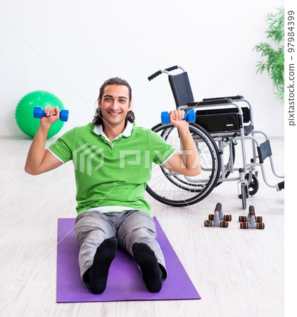 Young man in wheel-chair doing exercises indoors 97984399