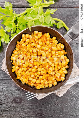Chickpeas stewed with vegetables in pan on dark board top Chickpeas stewed with vegetables in pan on dark board top 97984606