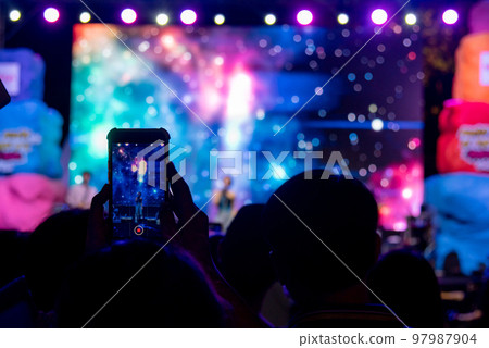 person using mobile smartphone taking photo festival music concert. 97987904
